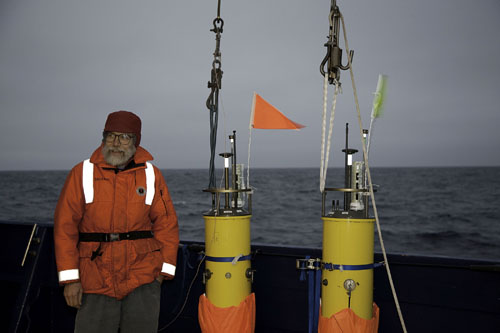 Barely visible against roiling seas: scientist Eric D'Asaro with robotic floats he developed.: Photograph courtesy of Craig Lee